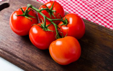 Kırmızı kareli havlu, sağlıklı gıda ile ahşap masa üzerinde taze olgun domates Şubesi.