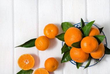 Meyve taze mandarin portakal veya mandalina ahşap masa üzerinde bir tabak içinde yapraklarla. Kopya alanı.