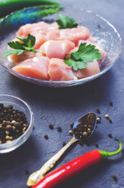 Karanlık taş tablo kase çiğ tavuk küpleri. Meme küpleri. Yumuşak seçici odak.