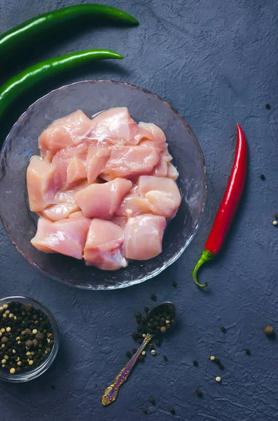 Koyu taş masada, kasede çiğ tavuk kübü. Göğüs küpleri. Boşluğu kopyala.