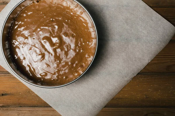 Çikolatalı hamur ve tahta kaşık ile kek tava koyu ahşap arka plan üzerinde Kapat.