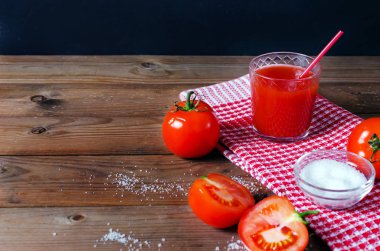 Taze domates ve tuz ile bardak domates suyu. Rustik ahşap arka plan.