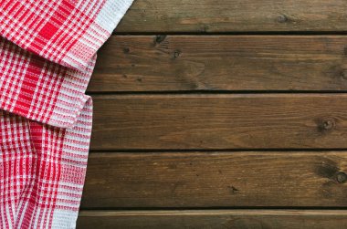 Kahverengi ahşap masa üzerinde kırmızı damalı piknik bezi.