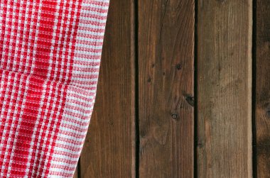 Kahverengi ahşap masa üzerinde kırmızı damalı piknik bezi.