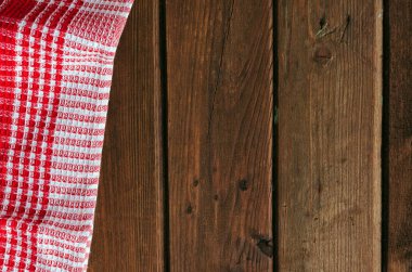 Kahverengi ahşap masa üzerinde kırmızı damalı piknik bezi.