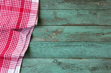 Turkuaz ahşap masa üzerinde kırmızı damalı piknik bezi.