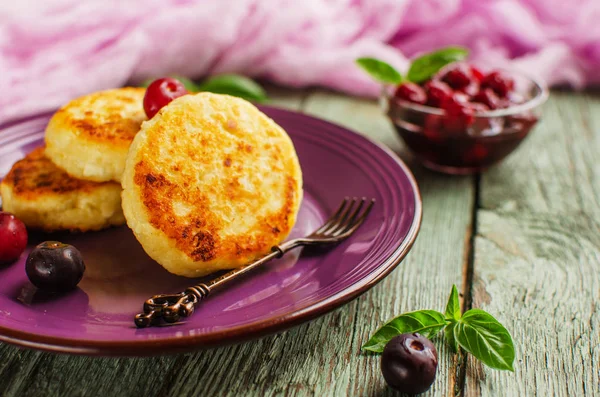 Cottage cheese pancakes on a dark background. Syrniki with fresh mint. Pancakes with cottage cheese on a lilac plate sprinkled . Homemade food