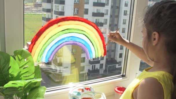 Fille peinture arc-en-ciel sur la fenêtre pendant la quarantaine à la maison. — Video