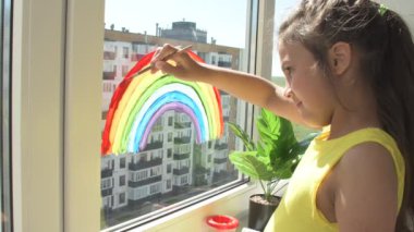 Evdeki karantina sırasında pencereye gökkuşağı çizen bir kız. Teşekkür ederim Temel İşçi Mesaj Konsepti.