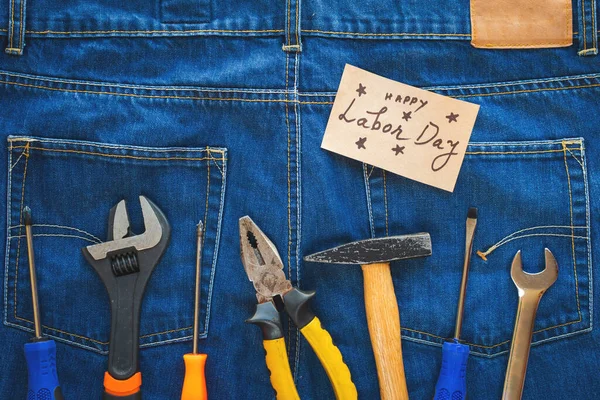 ABD İşçi Bayramı konsepti. Anahtarlarda farklı türler, kullanışlı araçlar, mavi kot pantolon arka planında etiket.
