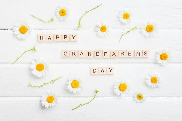 Glad morföräldrar dag bakgrund. Blommor på vit bakgrund och hälsningar. — Stockfoto