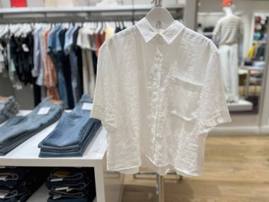 Mankenlerin ve giyim mağazasının önündeki askıda asılı sade ve şık bir beyaz gömlek..