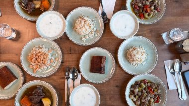 Restoran masasında çeşitli geleneksel yemekler. Tabağa yerleştirilmiş çeşitli Türk yemeklerinin üst görüntüsü.