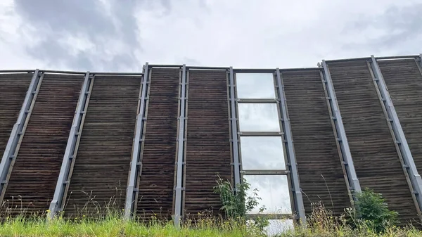 Bulutlu bir günde otoyolun kenarındaki tahta ve cam panellerden oluşan bir ses bariyeri..