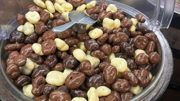 Sütlü çikolata ve beyaz çikolata kaplı kuru üzümlerin dolu bir kabın içinde görünmesi..