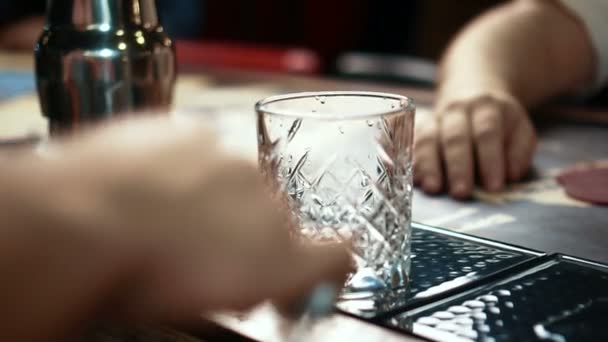 Gros plan du verre de whisky étant rempli de glace dans un bar élégant, au ralenti . — Video