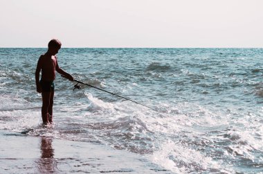 Sahilde bir olta ile bir çocuk silüeti