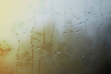 Sisli bardakta yağmur damlalarıyla el izleri.