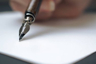 Kaligrafi kalemi beyaz kağıt üzerine mürekkeple yazılmış.