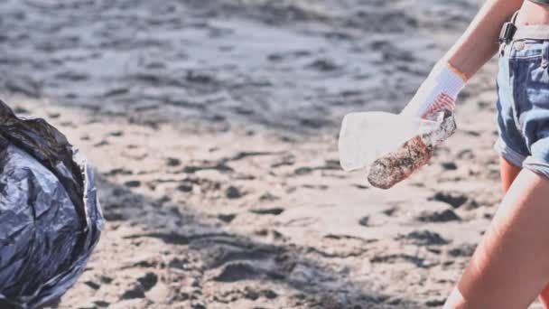 Группа добровольцев убирает пляж и сбрасывает мусор в мешок — стоковое видео