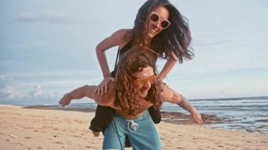 Çekici genç ve enerjik çift sahilde eğleniyor. Bir adam sürme ve gülüyor kadın sırtlama. Deniz yaz tatil mutlu romantik turist kavramı