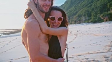 Çekici, aşk, Öpüşme ve ağır çekimde sarılma sahilde günbatımı zevk güzel genç seyahat çift. Deniz yaz tatil mutlu romantik turist kavramı.