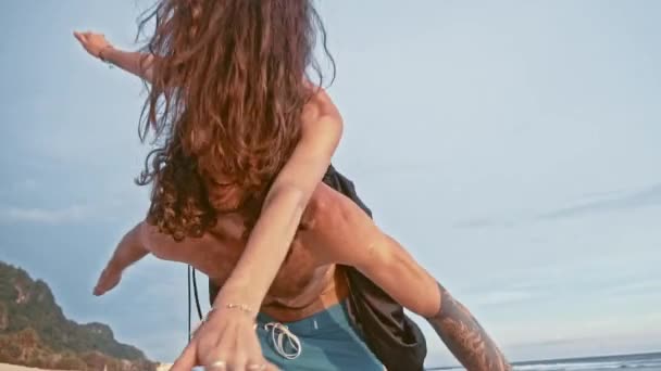 Ritratto ravvicinato di una giovane ed energica coppia che si diverte sulla spiaggia. Una donna cavalcando un uomo e ridendo. Vacanze estive al mare Felice concetto di turista romantico — Video Stock