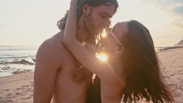 Привлекательная, влюбленная, красивая молодая пара путешествует, наслаждаясь закатом на пляже, целуясь и обнимаясь в замедленной съемке. Happy Romantic Tourrists концепция летнего отпуска моря . — стоковое видео
