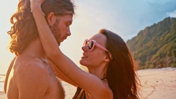 魅力的な恋に美しい若い旅行カップル スローモーションでハグとキスのビーチで夕日を楽しみます。海夏バカンス幸せなロマンチックな観光客のコンセプト. — ストック動画