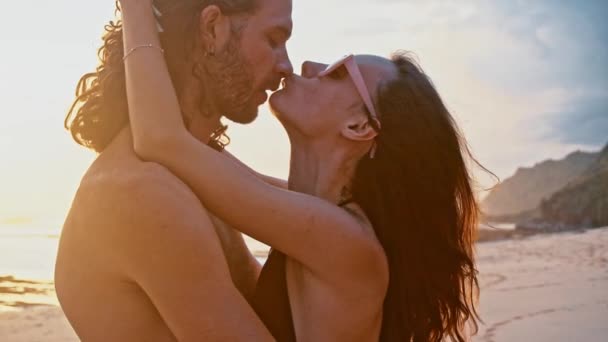 Attractive, in love, beautiful young travel couple enjoying sunset on the beach kissing and hugging in slow motion. Sea Summer Vacation Happy Romantic Tourists concept. — Stock Video