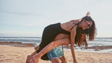 Çekici genç ve enerjik çift sahilde eğleniyor. Bir adam sürme ve gülüyor kadın sırtlama. Deniz yaz tatil mutlu romantik turist kavramı