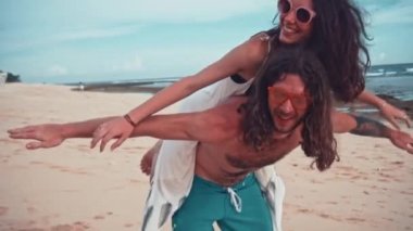 Çekici bir genç ve enerjik çift sahilde eğleniyor portresi kapatın. Bir adam sürme ve gülüyor kadın sırtlama. Deniz yaz tatil mutlu romantik turist kavramı