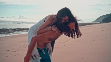 Çekici genç ve enerjik çift sahilde eğleniyor. Bir adam sürme ve gülüyor kadın sırtlama. Deniz yaz tatil mutlu romantik turist kavramı