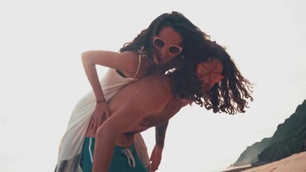 Close-up portret van een aantrekkelijke jonge en energieke paar plezier op het strand. Vrouw piggyback rijden een man en lachen. Zee zomer vakantie gelukkig romantisch toeristen concept — Stockvideo