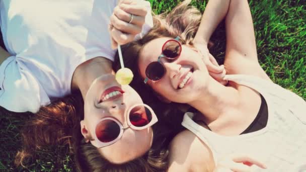 Pohled shora přátel mladá žena s bonbóny a zábavy, ležící na zádech sdílení cestovních dobrodružství, usmívající se smát v parku přímo shora - letní móda, volný čas a dovolené koncepce — Stock video