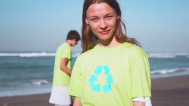 Dört gönüllü olarak görüntü geri dönüşüm ile yeşil tişört toplanan çöp torbaları ile fotoğraf makinesinde arıyorum kumsalda, çöp toplamak. Gönüllü ve kavram geri dönüşüm. Çevre bilinci kopya alanı