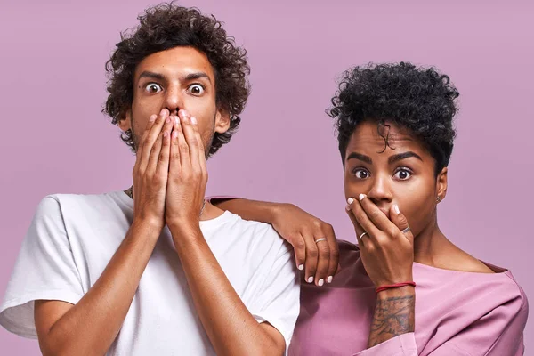 Horizontal tiro de chocado afro-americano jovem feminino e masculino olhar com assustado expressões na câmera, boca de cobertura, sendo atordoado para receber conta, não tem dinheiro para pagar dívidas — Fotografia de Stock