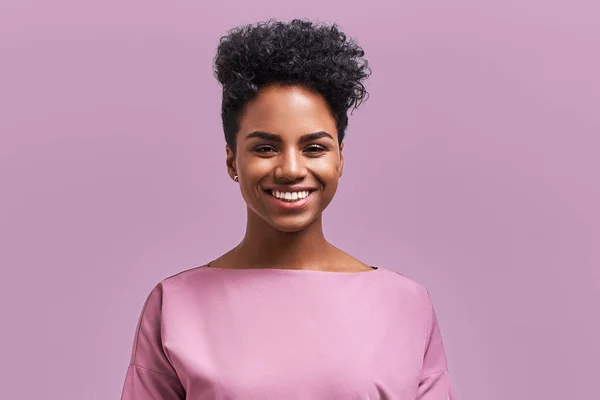 Empresária afro-americana feliz com sorriso positivo, tem cabelo escuro nítido, se alegra tendo fim de semana e bom descanso após a semana cansativa de trabalho duro, isolado na parede de lavanda — Fotografia de Stock