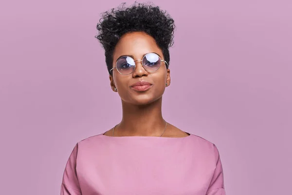 Empresária afro-americana feliz com sorriso positivo, tem cabelo escuro nítido, se alegra tendo fim de semana e bom descanso após a semana cansativa de trabalho duro, isolado na parede de lavanda — Fotografia de Stock