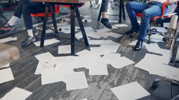 Upset business group of young people are bored in the office without work after a failure of business meeting. A woman with guitar setting on a table, two mens are playing with a phones. the paper is — Stock Video