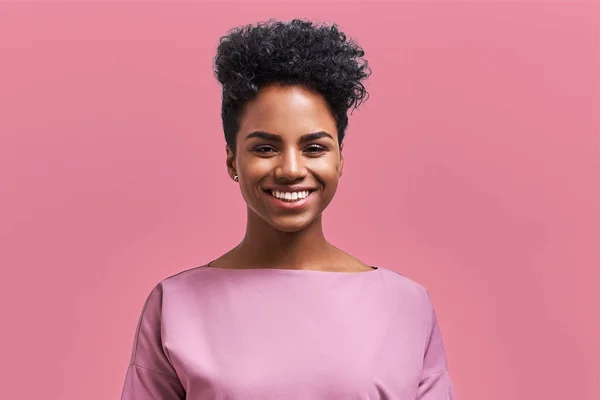 Empresária afro-americana feliz com sorriso positivo, tem cabelo escuro nítido, se alegra tendo fim de semana e bom descanso depois de trabalhar duro semana exaustiva, isolado na parede rosa — Fotografia de Stock