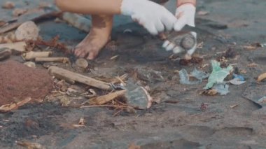 Closeup gönüllü sit ve sahilde çöp toplamak. Siyah plastik torba içine deniz sahilde temiz toplama çöp. Plaj Temizleme gönüllüler. Sahilde çöp toplama