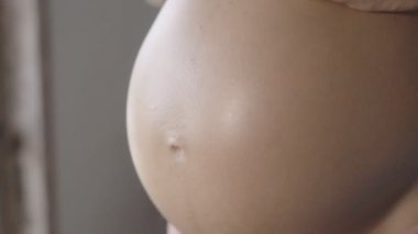 Hamile kadın güzel ışık sembolik el ile kalp şekli yapmak. Hamile Kadın bebeğinin yumru üzerinde bir kalp şeklinde ellerini tutarak. Gebelik, annelik, annelik ve beklenti kavramı.