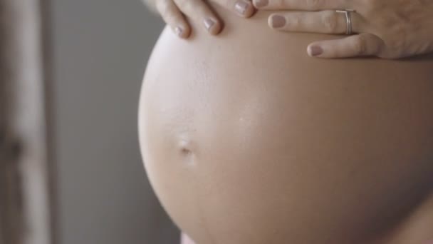 孕妇在美丽的灯光下用手做心形。孕妇在婴儿凸起时双手抱着心形。怀孕、孕产、生育和期望概念. — 图库视频影像