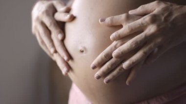 Anne ve babanın elleri hamile karnında. Hamile bir çift hamile karnını okşuyor. Mutlu bir aile. hamilelik, annelik, annelik, insanlar ve beklenti kavramı.