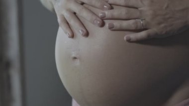 Hamile kadın güzel ışık sembolik el ile kalp şekli yapmak. Hamile Kadın bebeğinin yumru üzerinde bir kalp şeklinde ellerini tutarak. Gebelik, annelik, annelik ve beklenti kavramı.