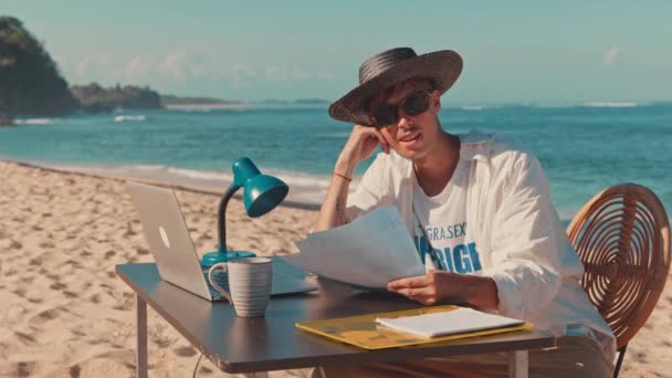 Jovem milenar remoto profissional trabalha longe do escritório na praia — Vídeo de Stock