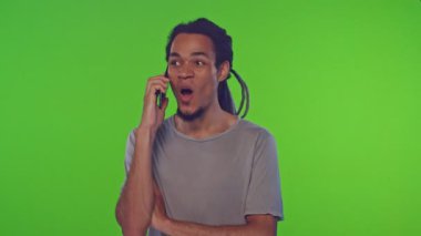 Yeşil ekranda akıllı telefonda konuşan uzun dreadlocks ile genç erkek portresi