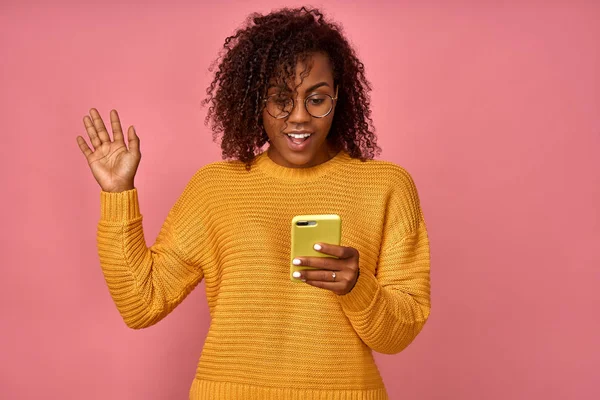 Heyecanlı siyah kadın model akıllı telefonda beklenmedik mesaj veya haber alır, akıllı telefon içine sevinçle görünüyor, aşırı sevinçli ifade vardır. Pozitif genç neşeli kadın cep telefonu komik fotoğraflar görüntüler