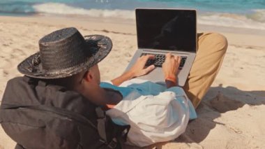 Genç profesyonel Freelancer veya turist omuz shot arkasına yakın, sahilde yalınayak yatıyordu, tatil zamanı sırasında ofiste uzaktan çalışmak. Konsept uzak kariyer, online dijital meslek beceri